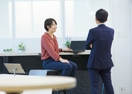 笑顔で同僚とコミュニケーションを取りながら仕事をする大北 幸奈の写真
