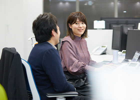 笑顔で同僚とコミュニケーションを取りながら仕事をする石塚 絵理の写真