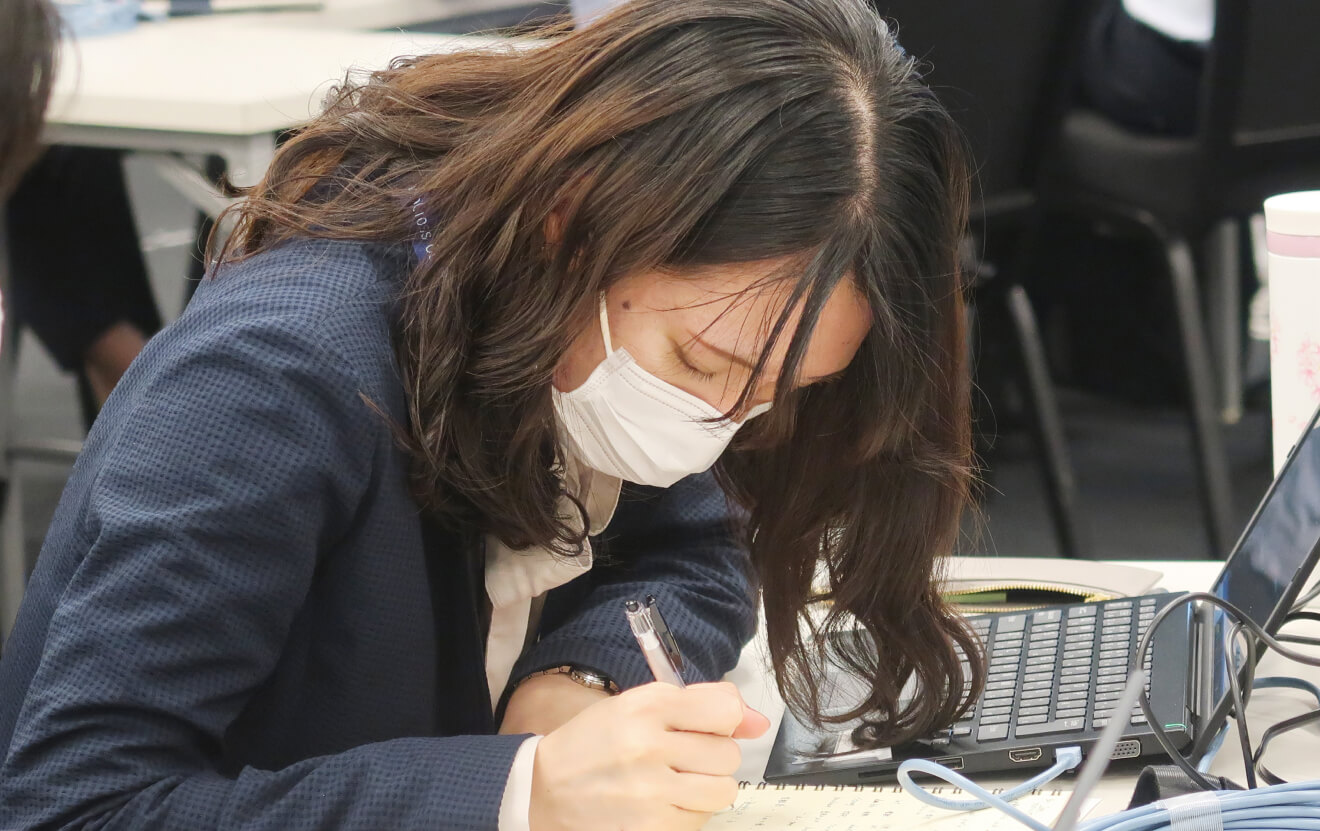 写真:研修中の社員。真剣な眼差しでノートにメモをとっている。