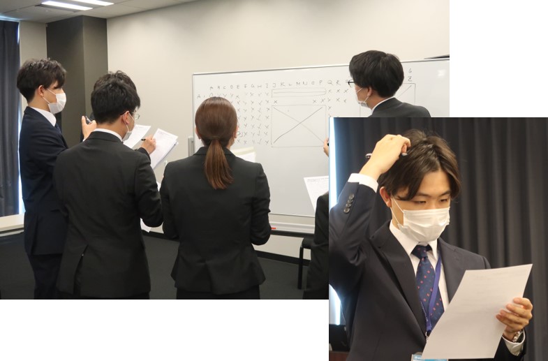 新入社員研修を受けている4人の後ろ姿とマスクをしている増渕 仁史の考えてる上半身の写真