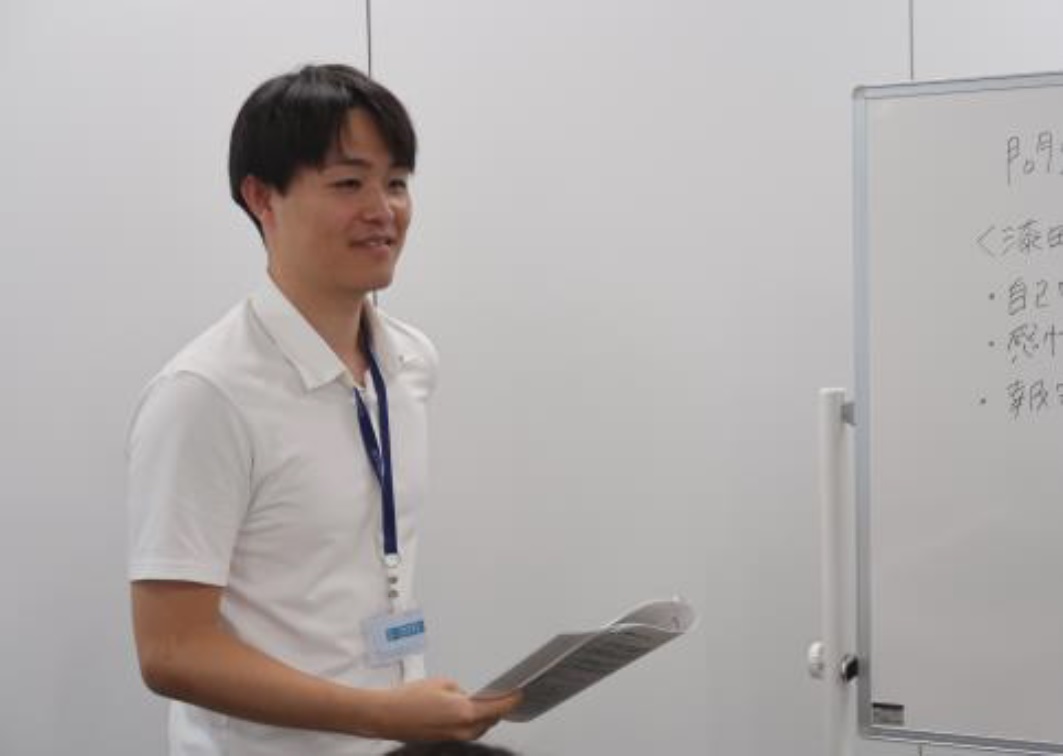 ホワイトボードの前で資料をもっている増渕 仁史の上半身の写真