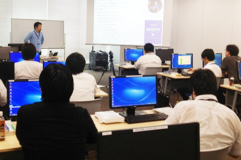 多くの社員が集まりPCを見ながら研修を受けている様子。